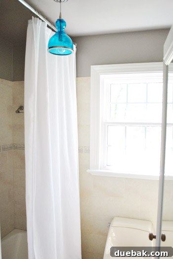 Upgrade Your Boob Light to a Modern Pendant 24 Full view of the installed blue pendant light in the brightened bathroom.