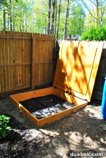Sandbox cover leaning against the fence, demonstrating the wide hinge rotation
