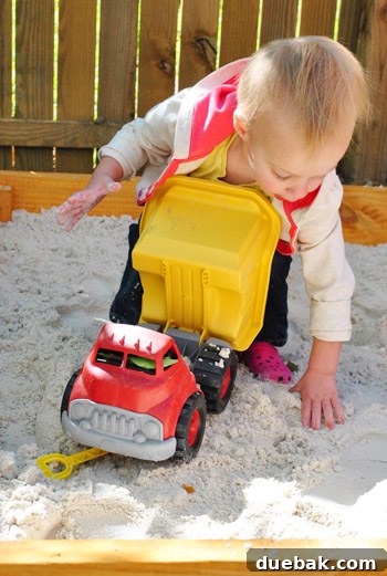 Close-up of Clara digging in the sandbox with a shovel