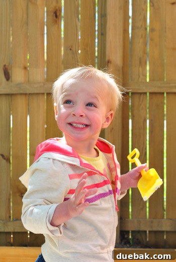 Clara smiling broadly while playing in the sandbox