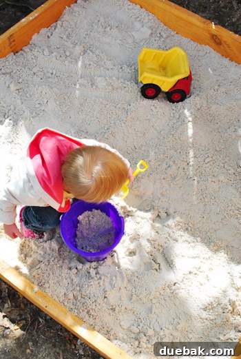 Clara playing in the shaded sandbox on the patio