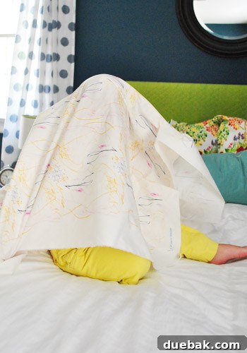 Clara playfully hiding underneath her custom-designed fabric, peeking out with a smile.