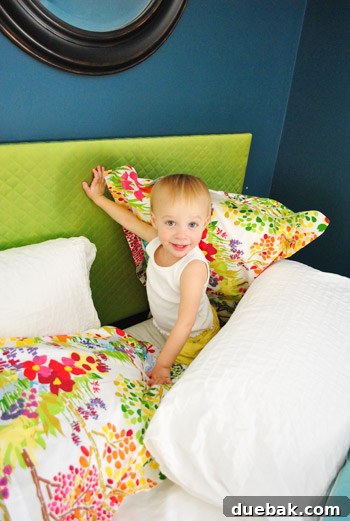Clara playfully 'popping out' from behind a pillow made from her custom fabric, with a wide smile.