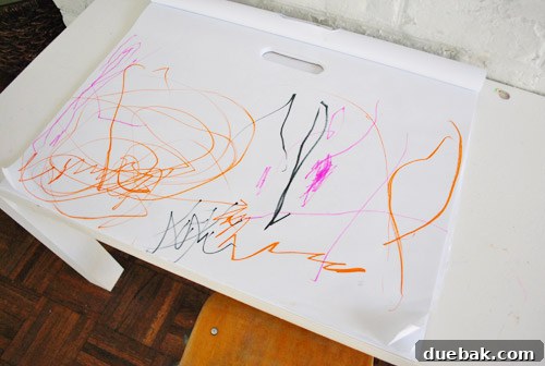Clara's complete drawing on a large sheet of paper, filled with vibrant scribbles in orange, pink, and black.