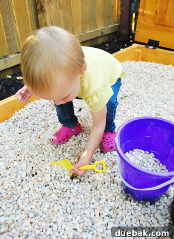 Clara happily digging in the pea gravel