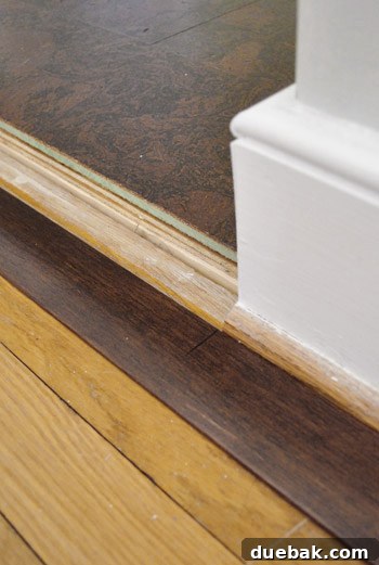 A hand holding a transition piece with a pen mark, ready to be cut with a miter saw.