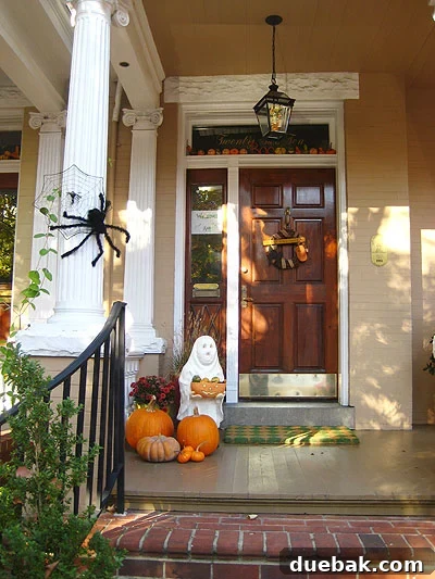 fanduringhalloween1 Historic home decorated for fall and Halloween with pumpkins, a hanging ghost, and a spider web, showcasing balanced seasonal decor.