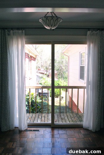 The narrow alleyway between the old and new sections of a house, looking towards the existing small, worn balcony.