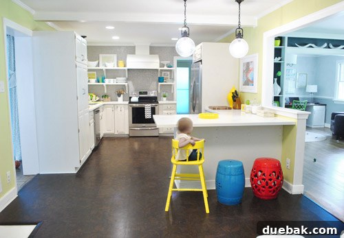 Clara's yellow highchair positioned in front of the kitchen peninsula, demonstrating a real-life yellow accent.