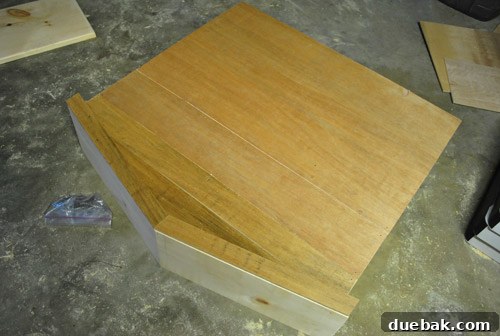 Dollhouse back panel partially covered with scrap wood strips, showing seams