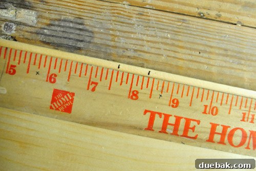 Wood panel with marks indicating wall placement for dollhouse assembly