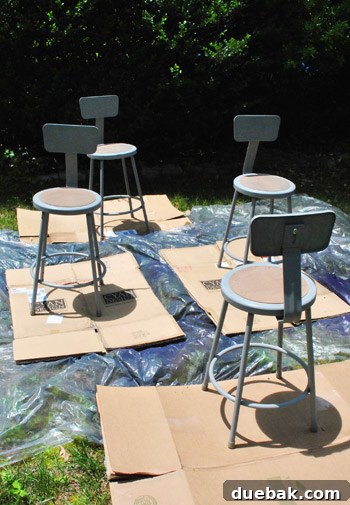 Metal Stool Makeover Spray Paint Edition 14 Stools set up outdoors on a tarp and cardboard for spray painting