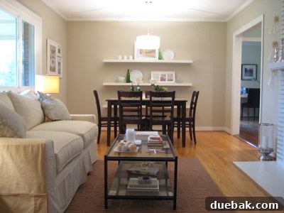 A wide shot capturing the entire living and dining room, showcasing the stunning impact of newly installed crown molding on the room's overall elegance and design.