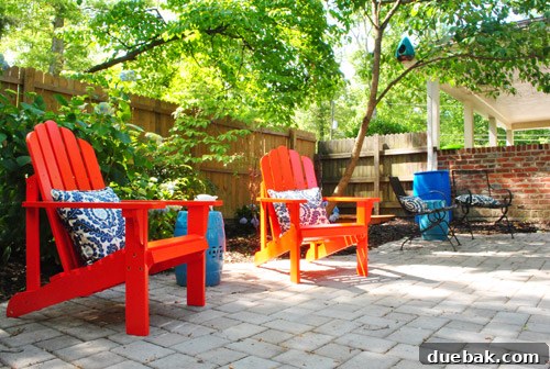 Bringing a Pop of Color to Our Side Patio with Red Adirondacks 19 Close-up of a red Adirondack chair with blue hydrangeas in the background