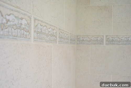 Outdated bathroom tile border featuring a repetitive tree motif in beige tones