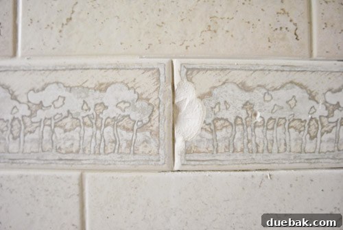 Chipped tile fragment flying off the wall during removal, emphasizing the importance of safety glasses