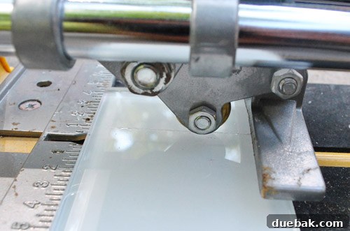 Snapping a scored glass tile perfectly using a manual tile cutter for a clean break