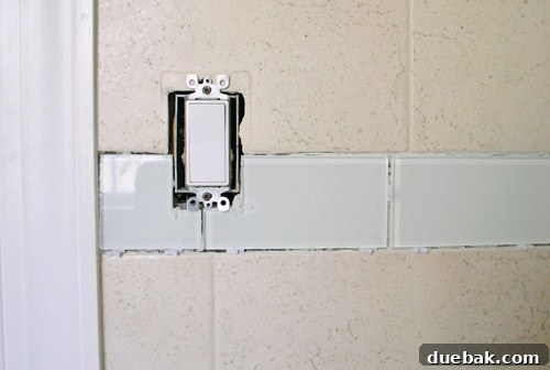 Newly installed glass tile border in the bathroom awaiting grout and sealant