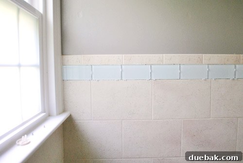 Bathroom tile border freshly installed, allowing thinset to cure completely before grouting