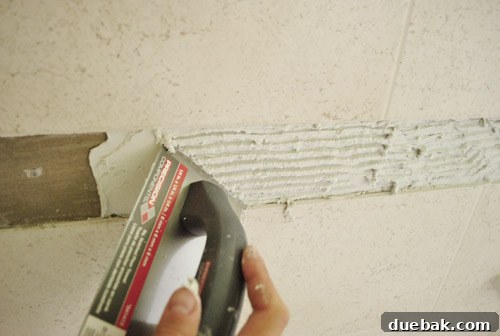 Carefully placing clear glass subway tiles on the bathroom wall with spacers