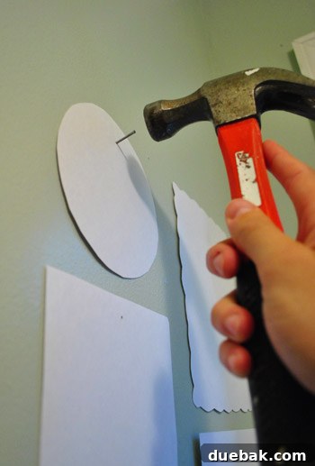 Every Year, A New Frame 11 Hammering a nail through the marked guide hole on a paper template on the wall