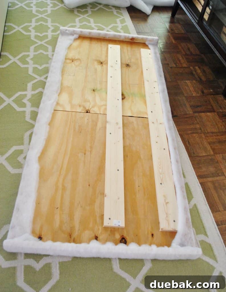 Finished batting stapled to back of DIY headboard frame, showing the first completed layer