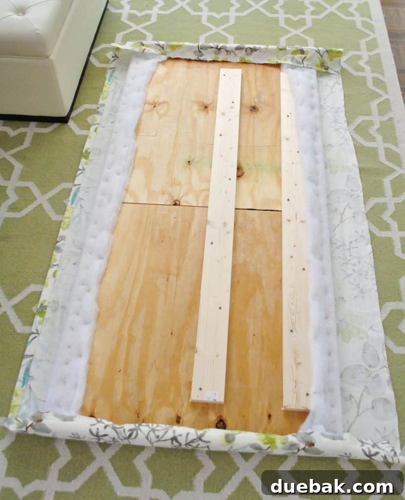 Both ends of fabric headboard stapled around back of wood frame, showing initial fabric attachment