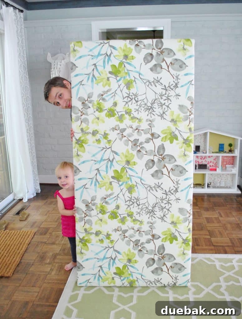 John standing proudly with finished DIY fabric headboard, showcasing its plush and tight upholstery