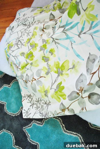 A swatch of botanical print fabric laid on top of a patterned turquoise rug