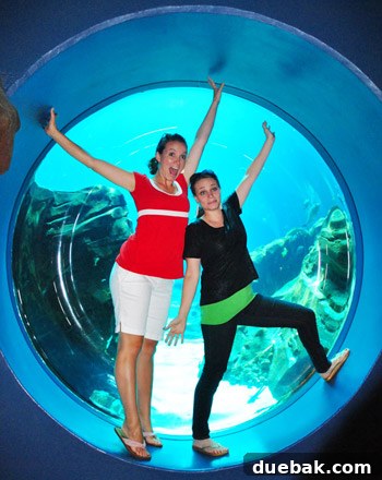 Woman making a funny face and jazz hands in an aquarium viewing bubble