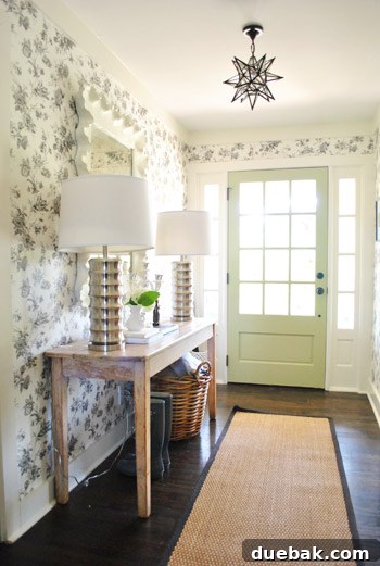 Vibrant Home Breakthrough 2 Elegant foyer with scalloped mirror, patterned wallpaper, and sophisticated lighting in a Roswell, Georgia home.