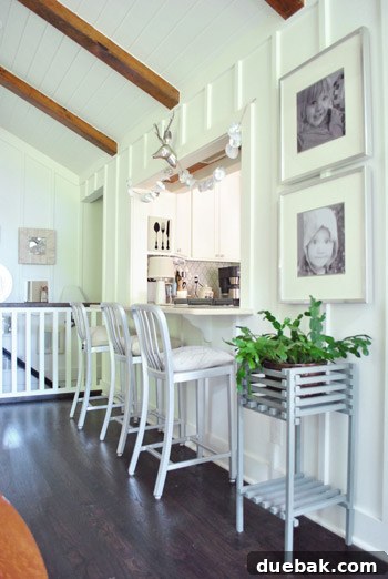 Vibrant Home Breakthrough 9 Kitchen pass-through with framed children's portraits and Crate & Barrel stools.