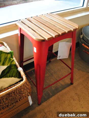 A red stool with a slatted wooden top.