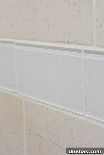 Detailed shot of the new clear glass border tiles sparkling with water droplets in the shower.