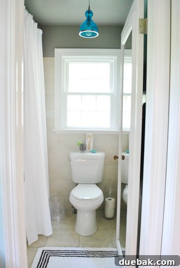 After photo of the master bathroom, showcasing a fresh paint color, modern light fixture, and updated decor.