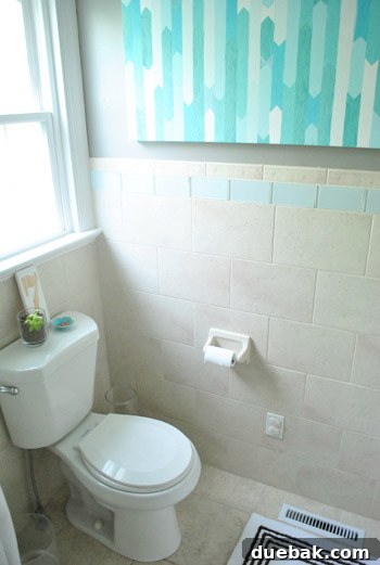 The 'after' view from the same angle, demonstrating how darker walls, white trim, and a new toilet dramatically improve the room's appeal.