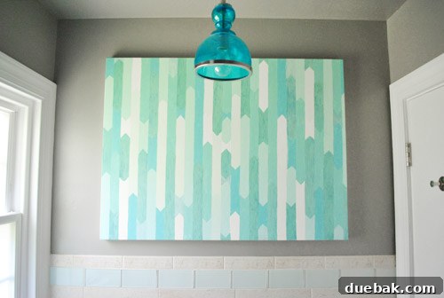 After image with a beautifully centered blue pendant light and DIY artwork replacing the old fixtures, enhancing the wall.