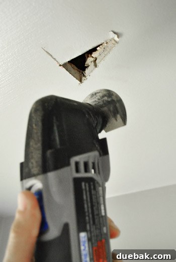 Cutting a small exploratory hole in the drywall ceiling to check for beams