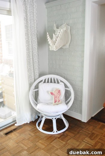 The newly painted white egg chair in the living room, styled with temporary white towel-covered cushions and a pig pillow.