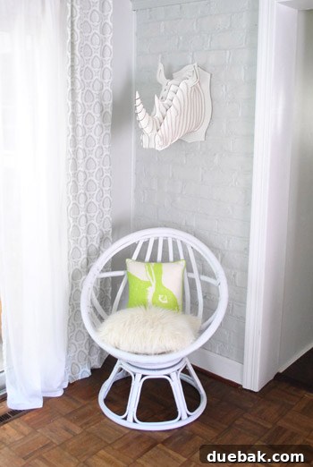 The egg chair styled for summer with a faux fur pillow on the bottom and a bunny pillow on the back, with Burger still nearby.