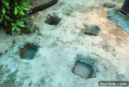 Freshly poured concrete footings in deck post holes at dusk