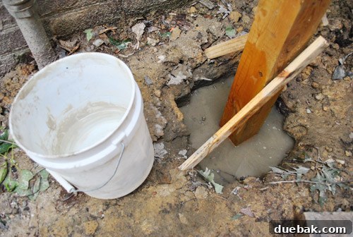 Water being added to Quikrete no-mix concrete around a deck post