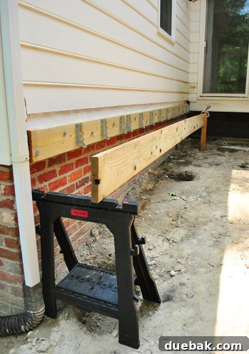 Man working alone on setting a long girder board for a deck