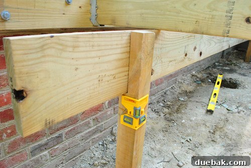 Deck girder resting in a notched post, being checked for levelness