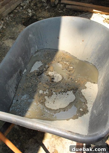 Mixing concrete in a wheelbarrow with a garden hoe