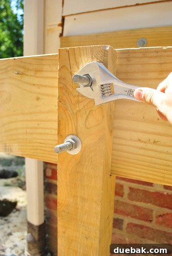 Tightening nuts on through-bolts securing the girder to a deck post.