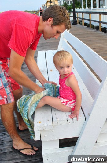 Bethany Beach Bliss: A Delaware Getaway 33 Clara, covered in sand, being gently cleaned off by her father.