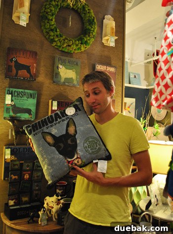 Seaside Treasures: Browsing Beach Boutiques and Thrifted Gems 22 John holding a decorative pillow with a chihuahua image on it