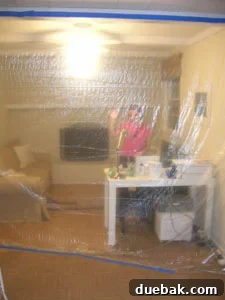 Sherry stands proudly next to a plastic-sealed doorway, part of a temporary dust-protection barrier during home renovation.