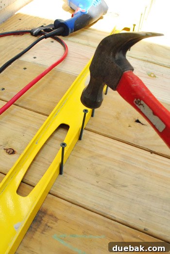 The Foundation of Your Deck 20 The author using a hammer to start screws and a level for alignment before drilling them in.